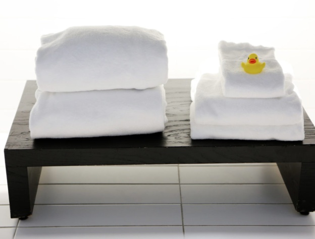 Close up image of two piles of towels on a dark wood bench